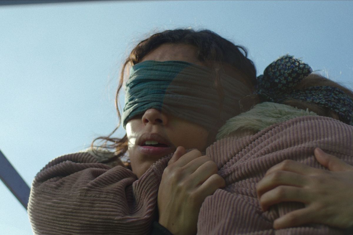 A blindfolded woman (Georgina Campbell) clutches a blindfolded blond child in closeup in Netflix’s Bird Box spinoff Bird Box Barcelona