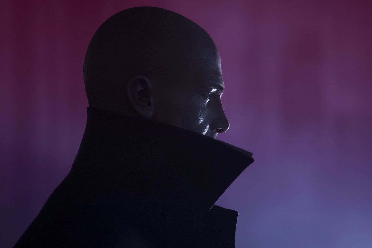 Profile image of bald man against a dark purple tinged background