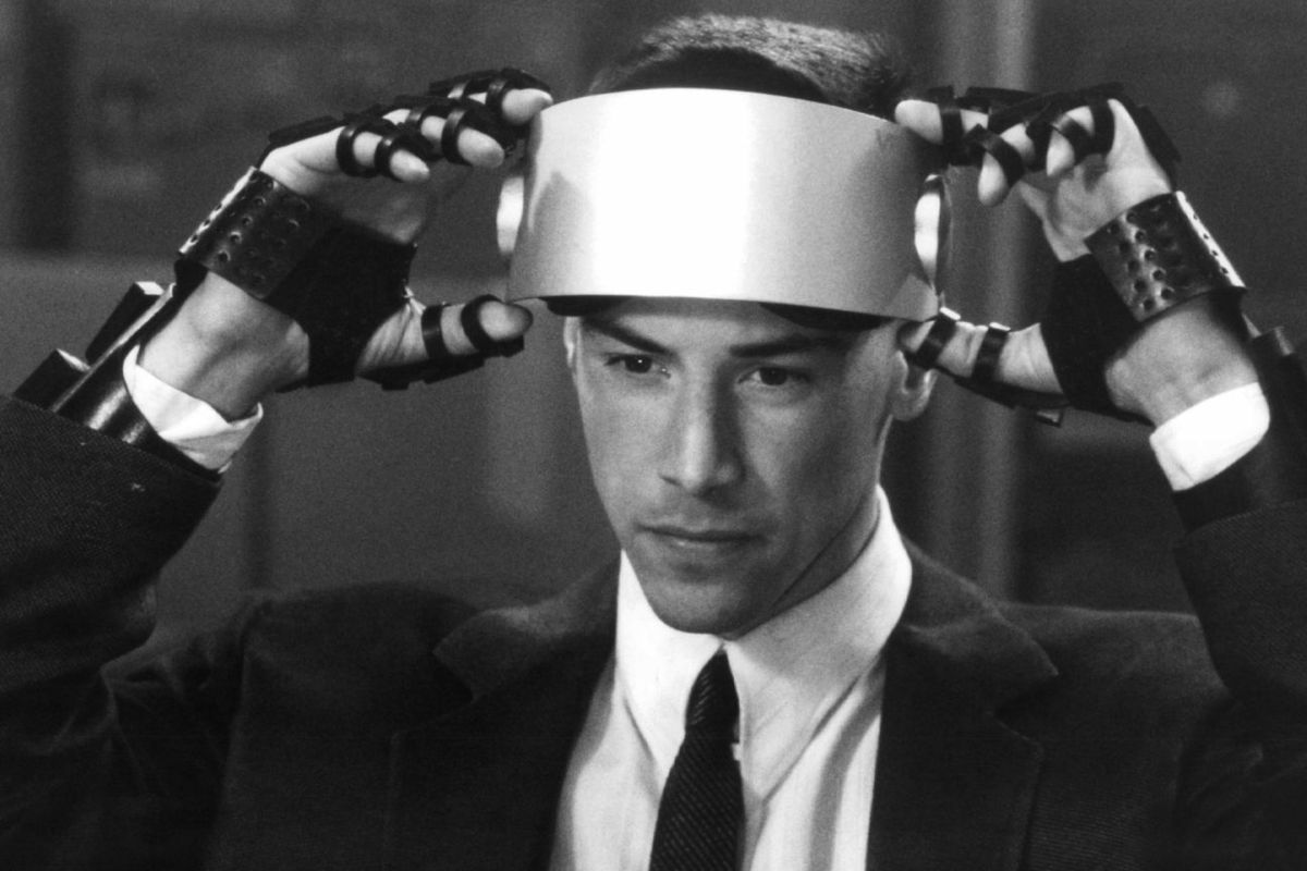 Keanu Reeves as Johnny Mnemonic putting on a VR headset with metallic gloves in Johnny Mnemonic: In Black and White.